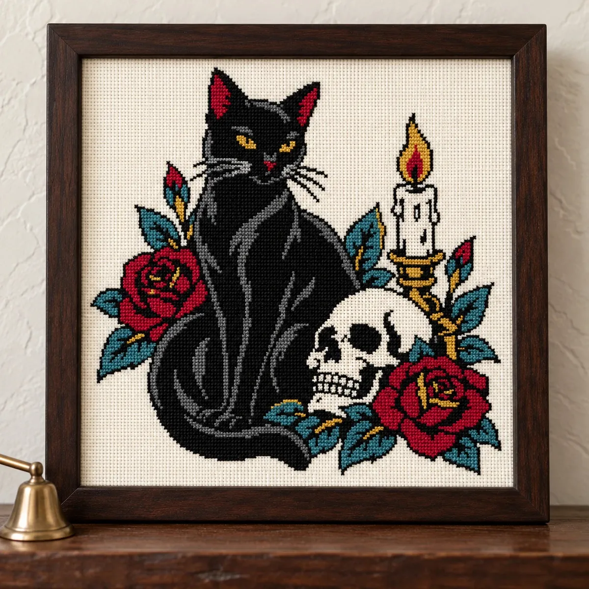 Black cat with a skull, candle and red roses, cross stitch in a dark wood frame on a shelf