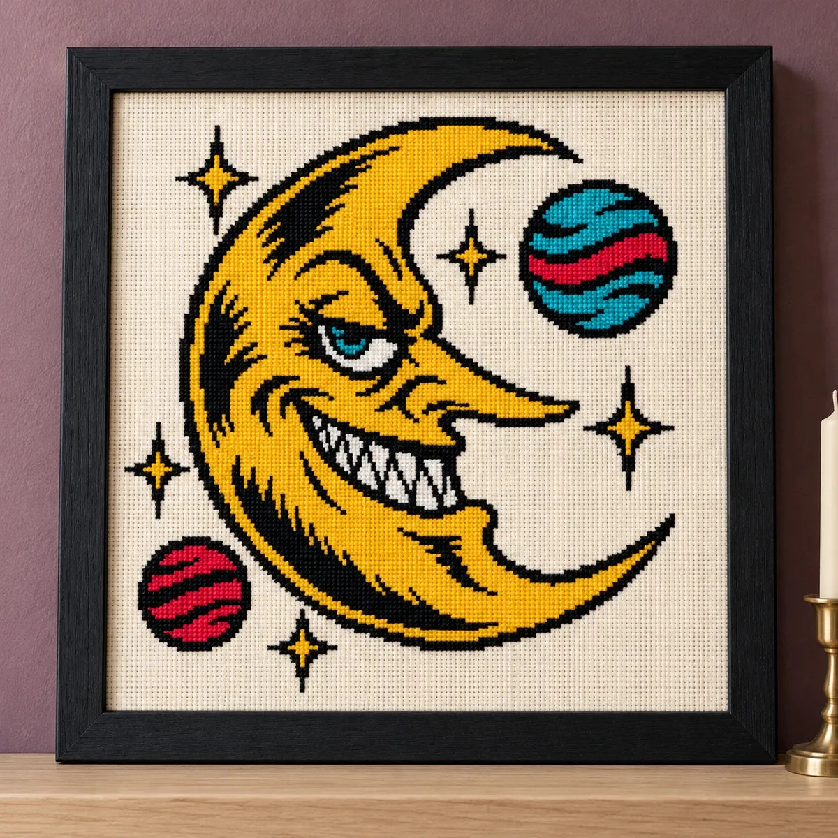 Straight-on view of the finished Crescent Moon Cross Stitch in a black frame on a wooden shelf