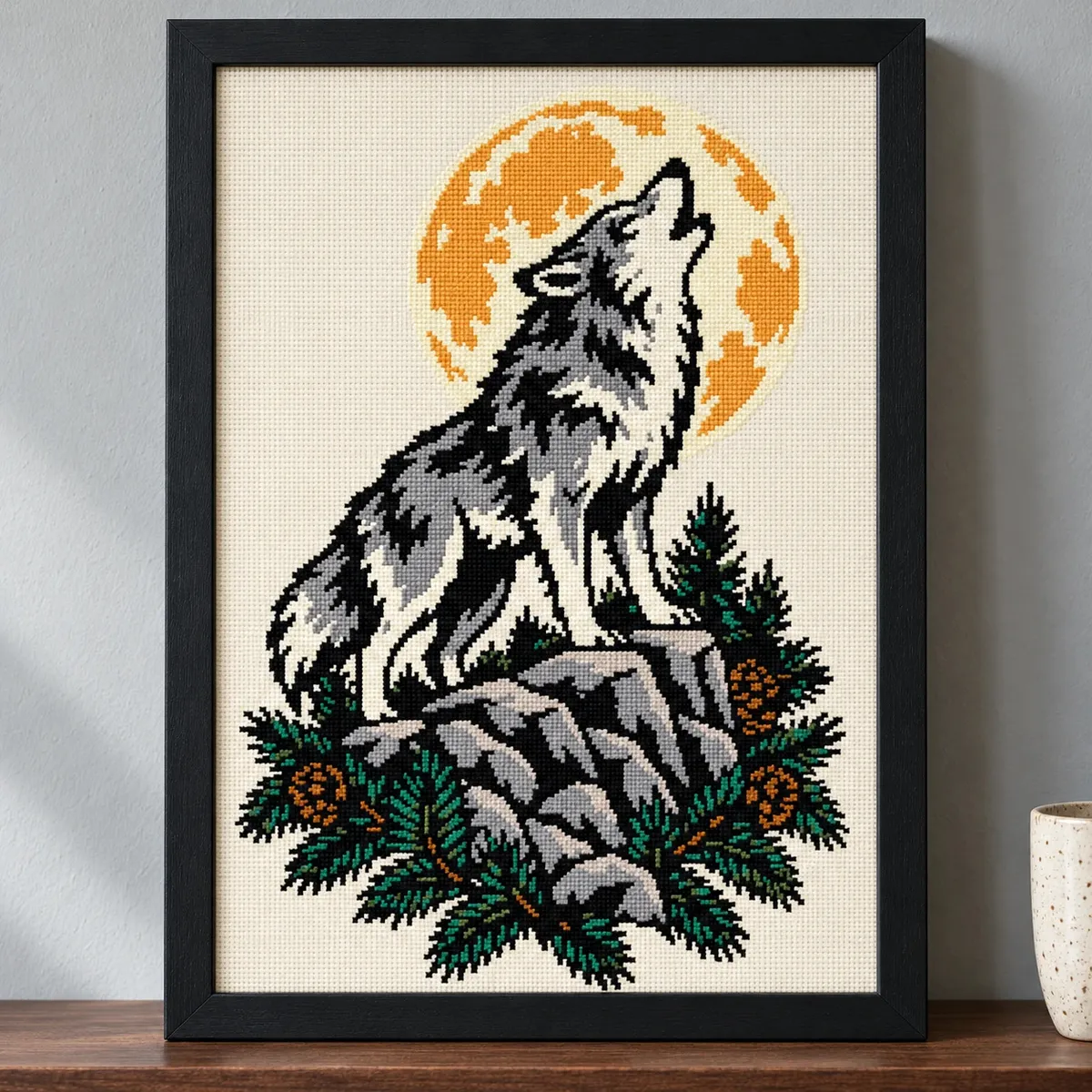 Straight-on view of the finished Howling Wolf Cross Stitch in a black frame on a wooden shelf