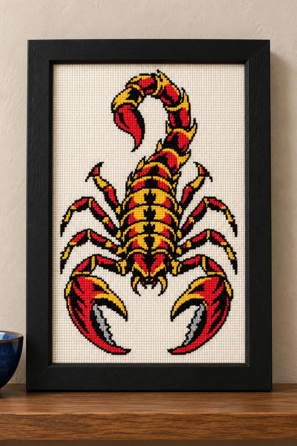 Straight-on view of the finished Scorpion Cross Stitch in a black frame on a wooden shelf