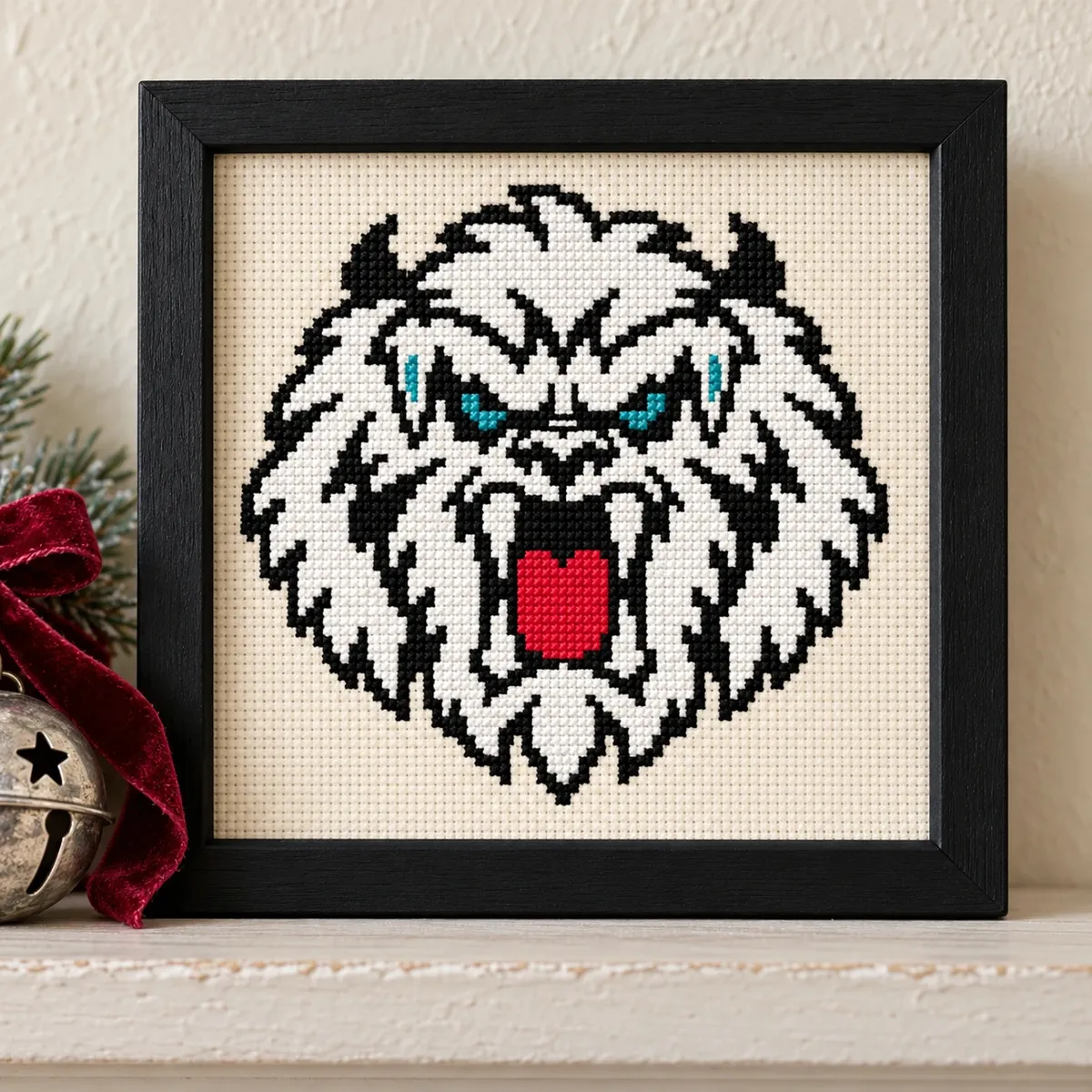 Straight-on view of the finished Yeti Cross Stitch in a black frame on a wooden shelf